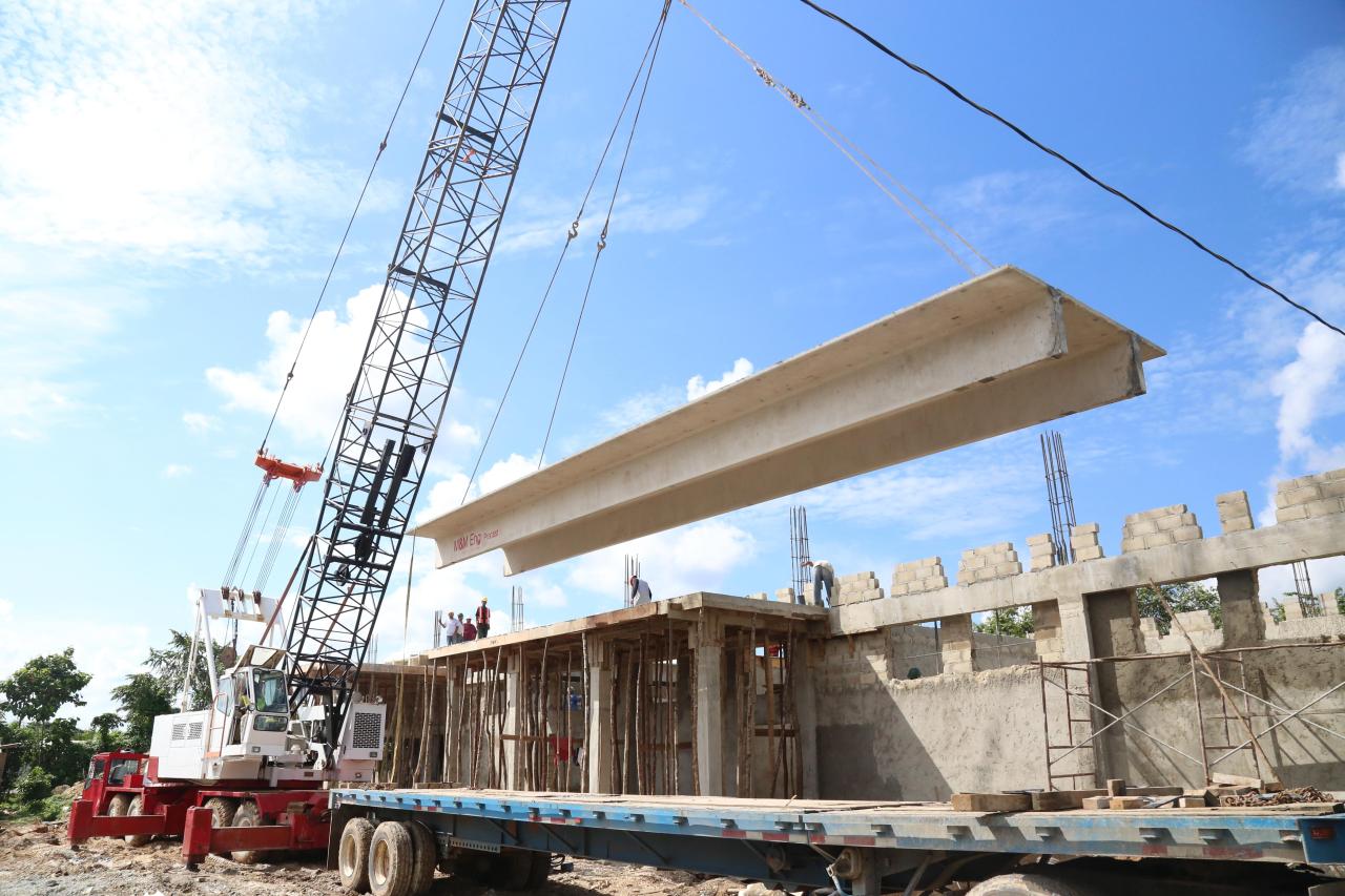 Crane lifting a concrete beam during UNOPS hospital construction in Belize