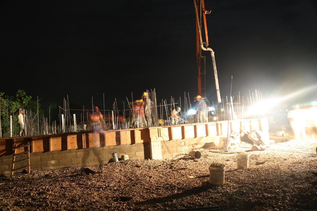 Night-time concrete placement under floodlights during UNOPS hospital construction in Belize